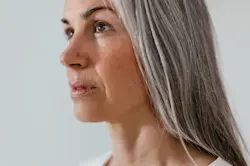 Close-up of woman in profile with long straight grey hair. AW135