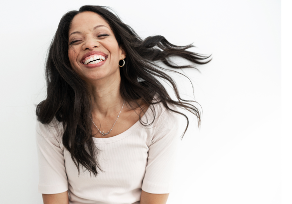 Biracial woman tossing her hair back and smiling with eyes closed on white background O-mazing woman