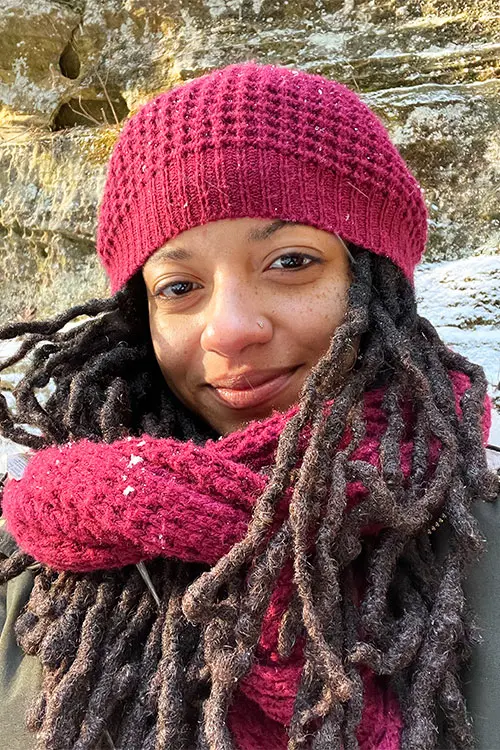 Kristin Lynem portrait in a pink knit hat and scarf in snow.