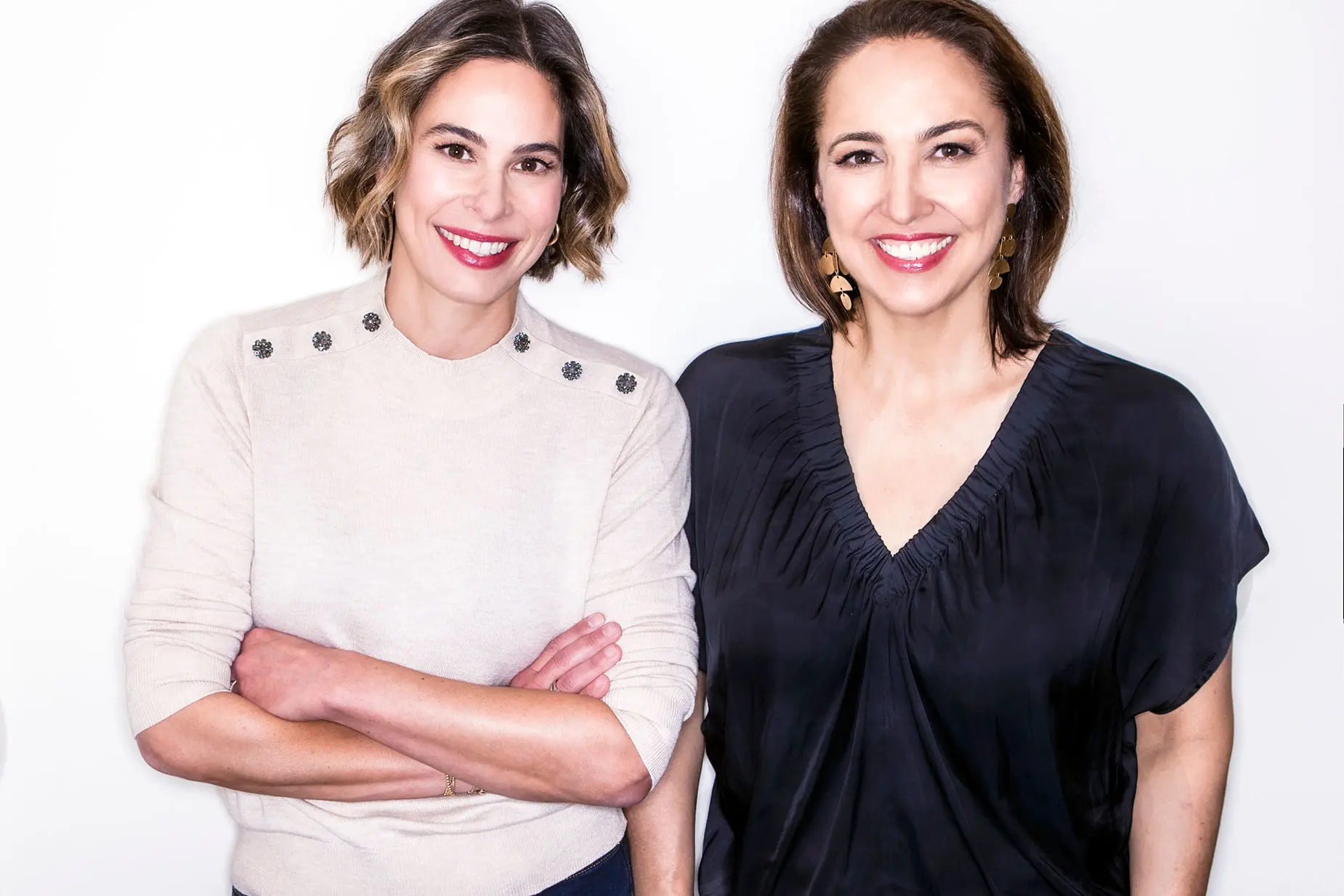 Portrait of Monica Molenaar and Anne Fulenwider standing shoulder to shoulder smiling on white background.