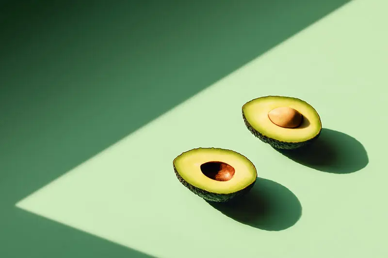 Halved Avocado on green background. AW555