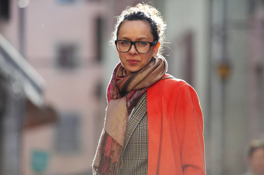 Woman standing on city street in winter clothes and glasses with neutral expression. AW275