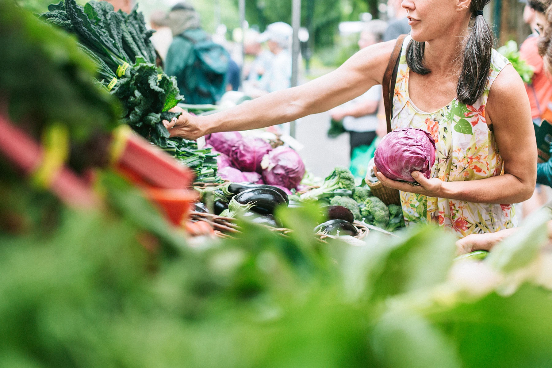 Grey haired woman in pigtails shopping for vegetables at a green market. AW534