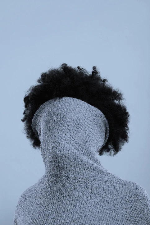 Turtleneck sweater covering face of woman of color. AW215