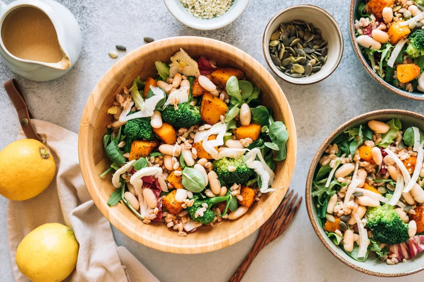 Overhead view of fresh vegetable, grain and nut salad, lemons and dressing on the side. AW148