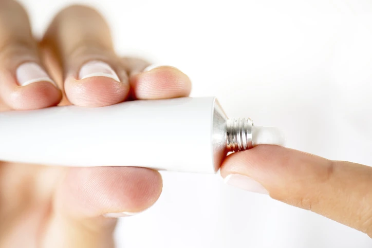 AW074 Estradiol Vaginal Cream (photo of a woman holding tube of cream, applying to finger)