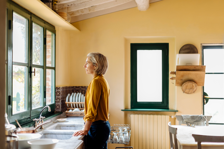 AW276 Does Menopause Cause Fatigue? (photo of a woman with greyish blonde bobbed hair in kitchen looking out the window)