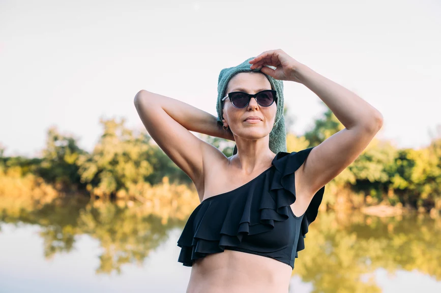 Stylish woman in a swimsuit and sunglasses, hair wrapped in towel at lake. AW121 