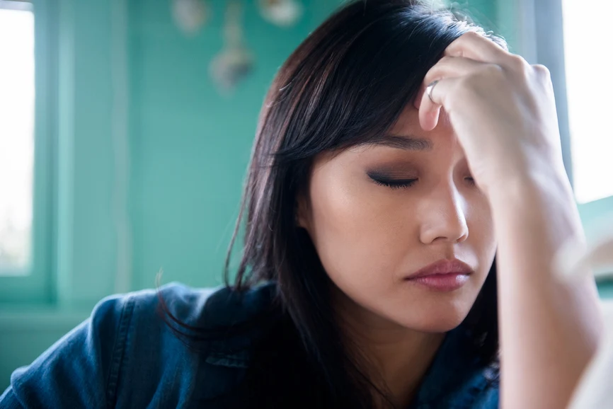 Asian woman touching her forehead in distress. AW108