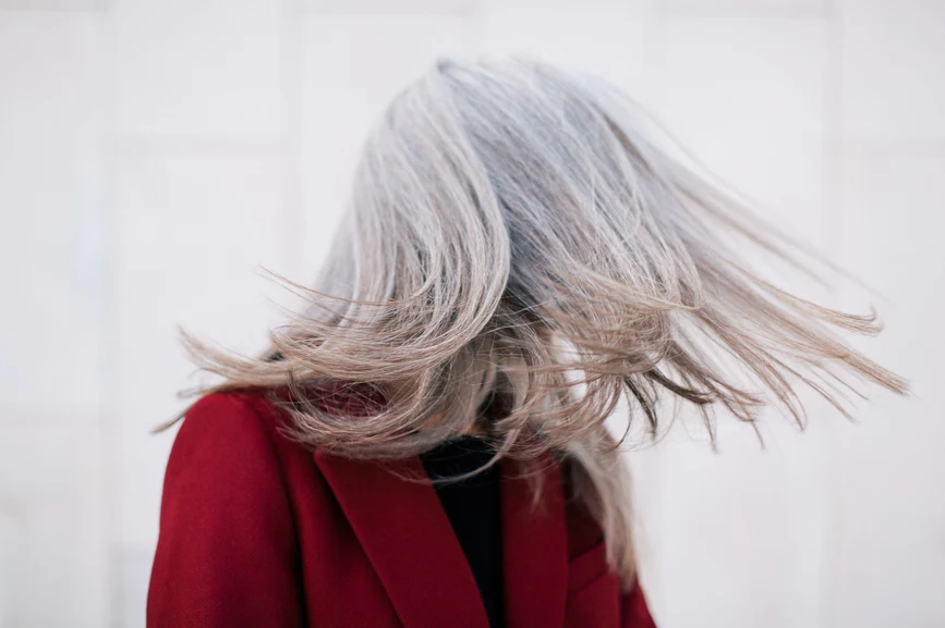 Woman flipping long straight grey hair while turning her head in motion. AW089