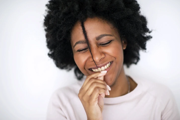 Middle-Age Black woman pulling playfully on her hair smiling. AW237