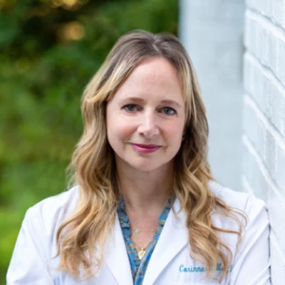 Dr. Corinne Menn headshot, in lab coat, outdoors.