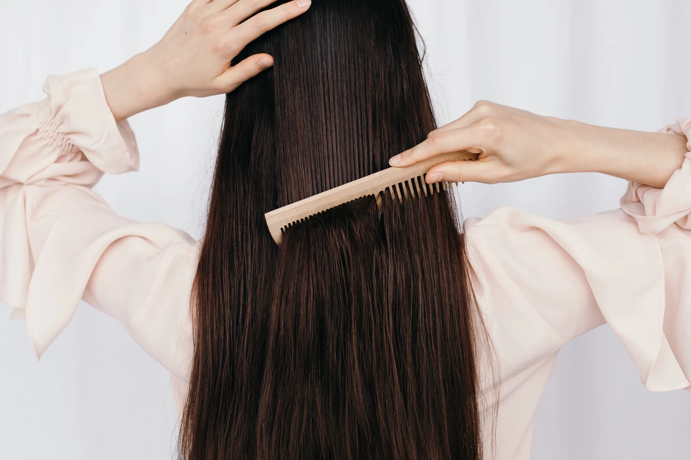 Rear view of woman combing long mane of dark hair in silk blouse. AW168