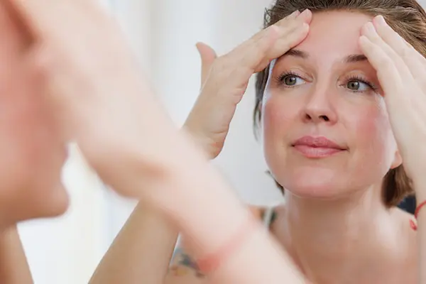 AW867 Reflection of a woman massaging her forehead in a bathroom mirror. (thumbnail_