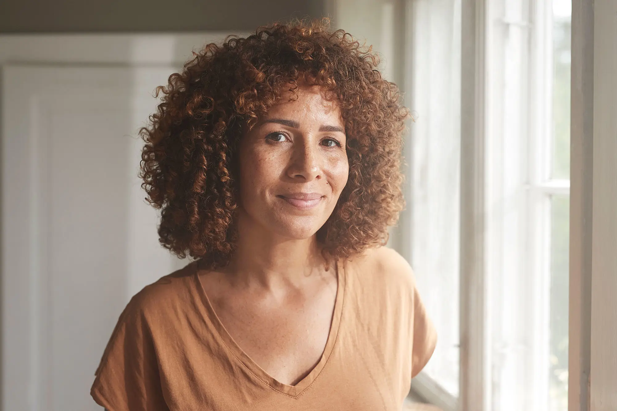 Content looking bi-racial woman looking at camera in her home. AW513