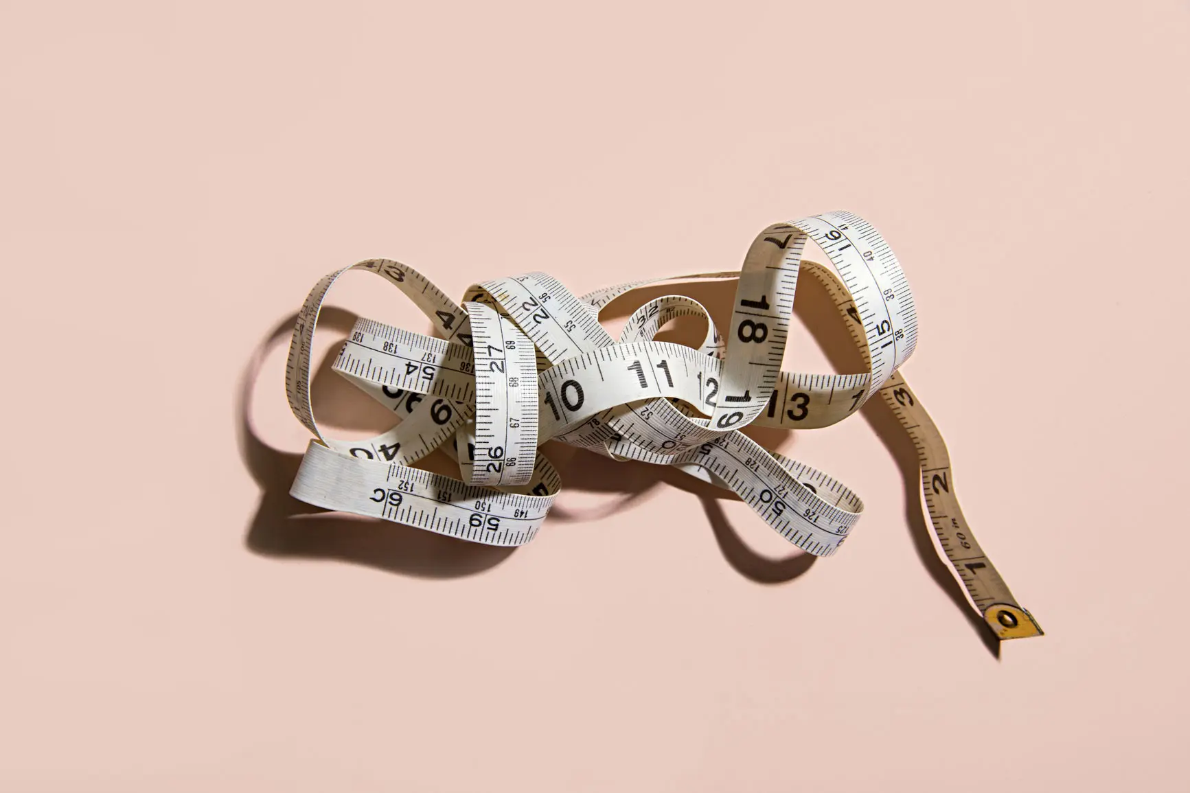 Crumpled measuring tape on light peach background. AW207