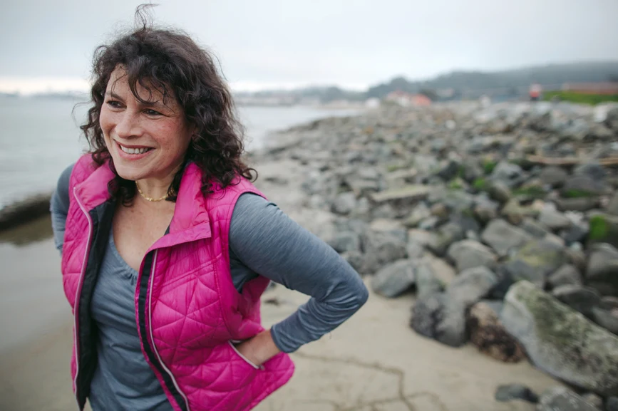 Woman at rocky beach in vest after a run. AW243