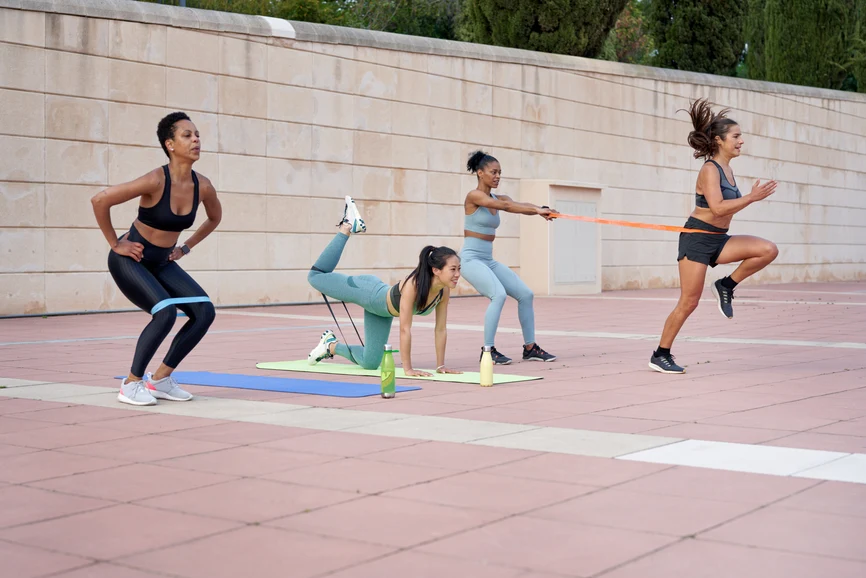 Racially diverse group of women doing high impact exercise in park. AW147