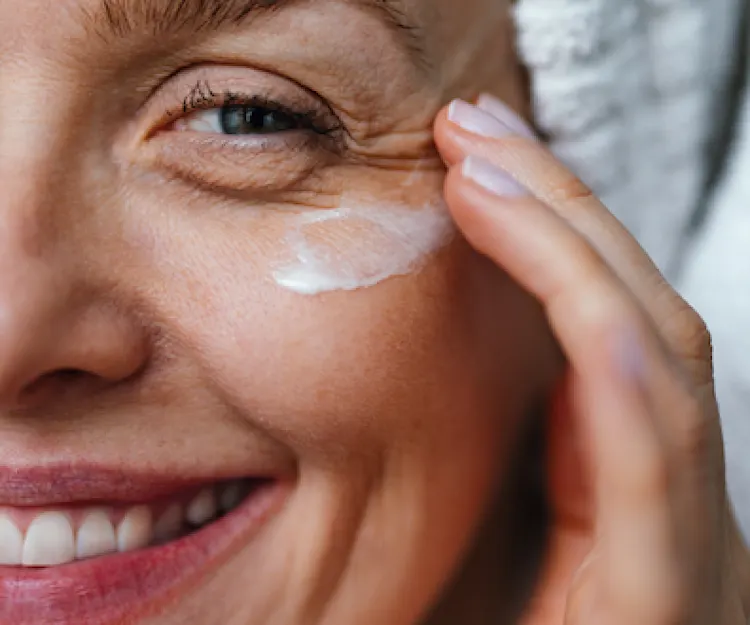 Woman smiling putting on eye cream