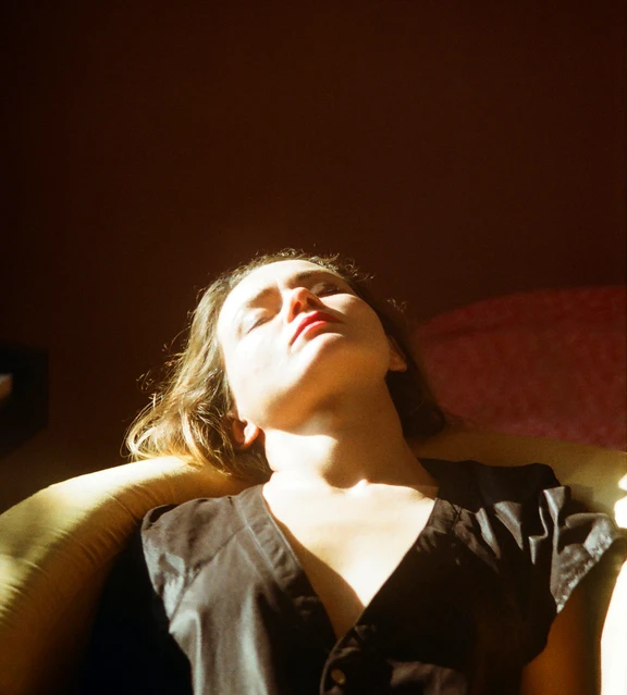 Woman resting her head back in discomfort with closed eyes bathed in bright light. AW107