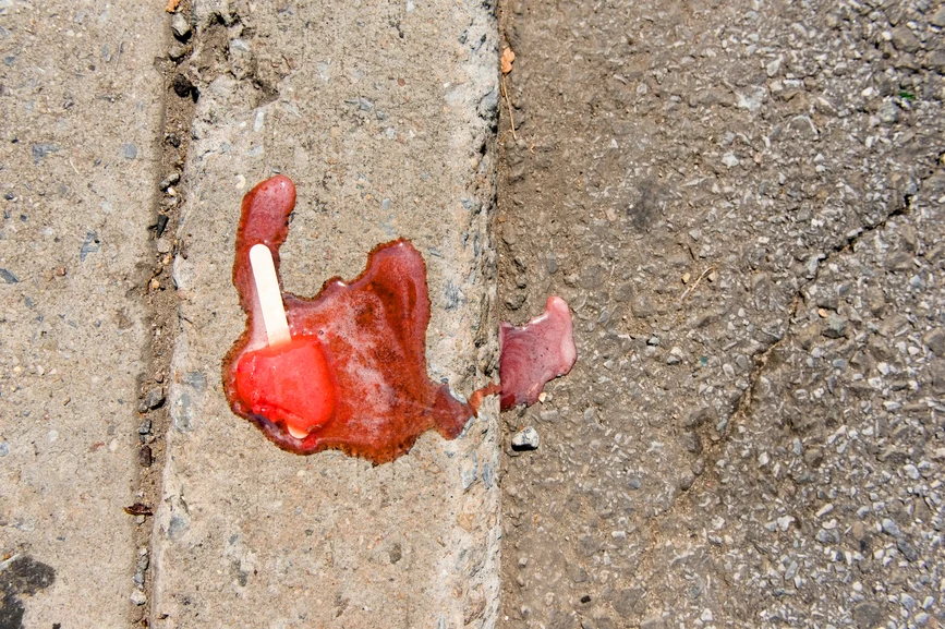 Melted red popsicle on pavement. AW065 