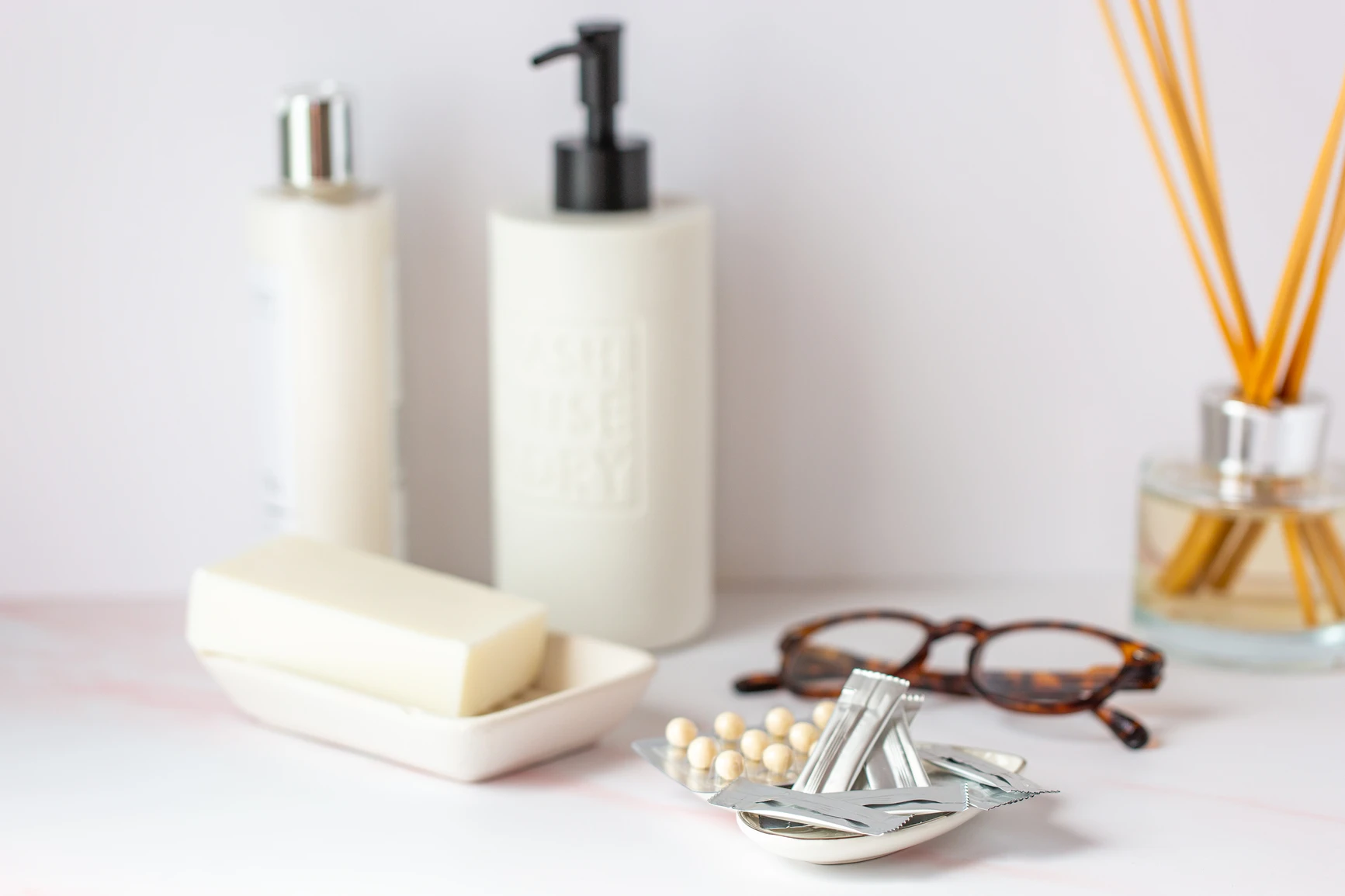 Bathroom vanity with still life of beauty products, eyeglasses and a tray of estrogen and progesterone products. AW175 