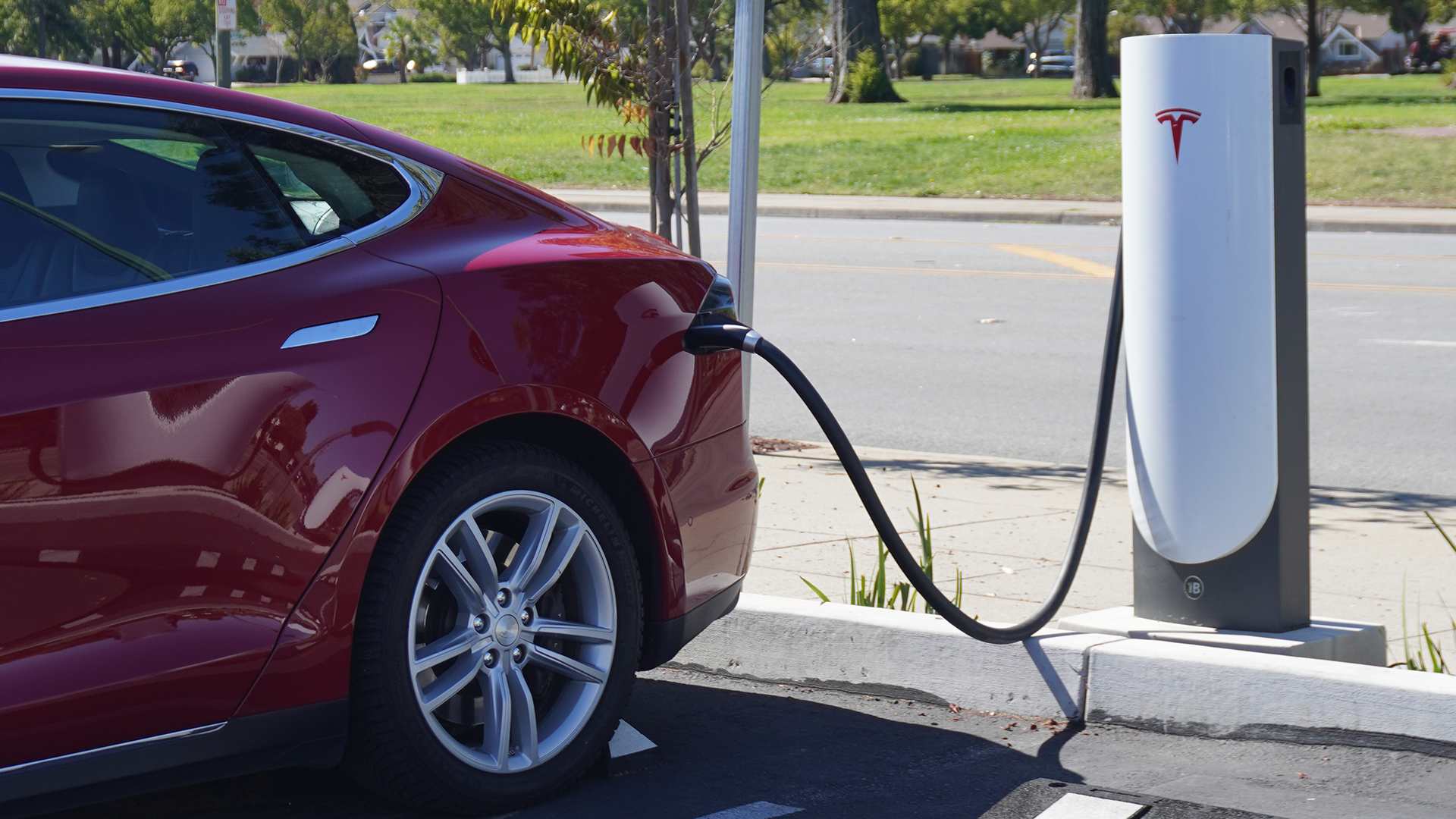 A red tesla car is plugged into a charging station.