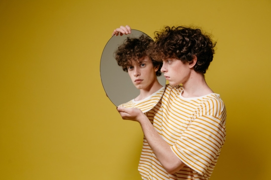 Man looking at his skin while holding a mirror