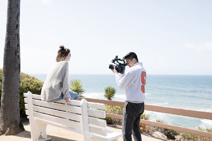 Cameraman taking video of woman sitting on bench