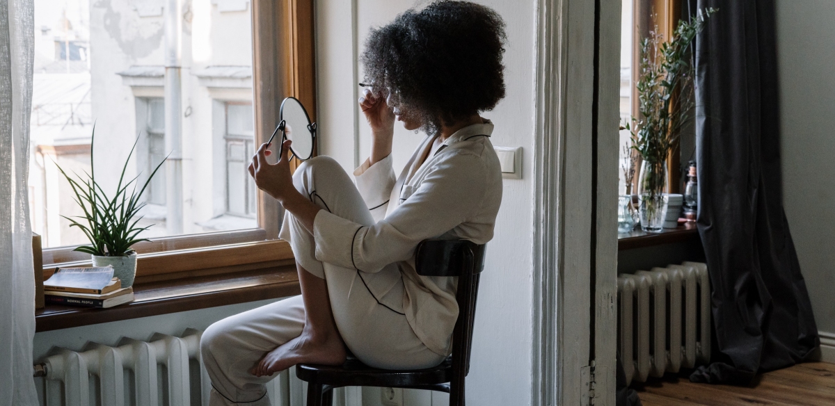 Woman looking into mirror doing makeup 