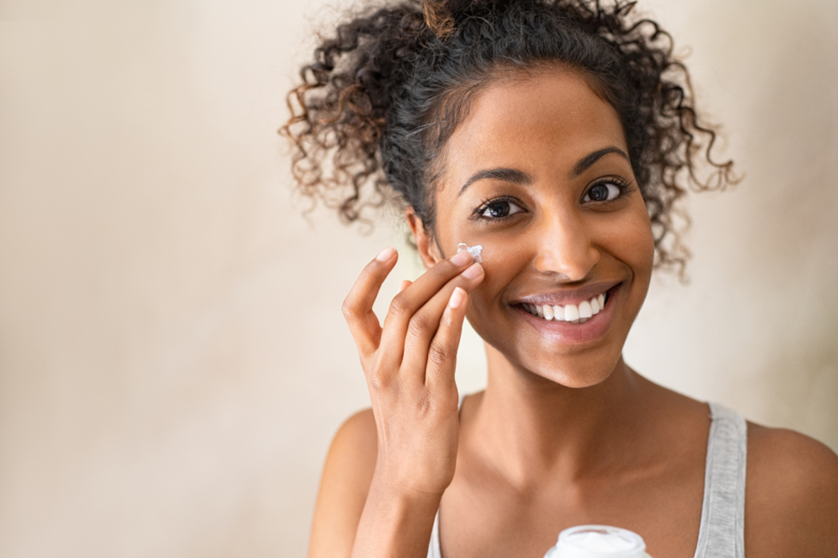 happy woman applying moisturizer