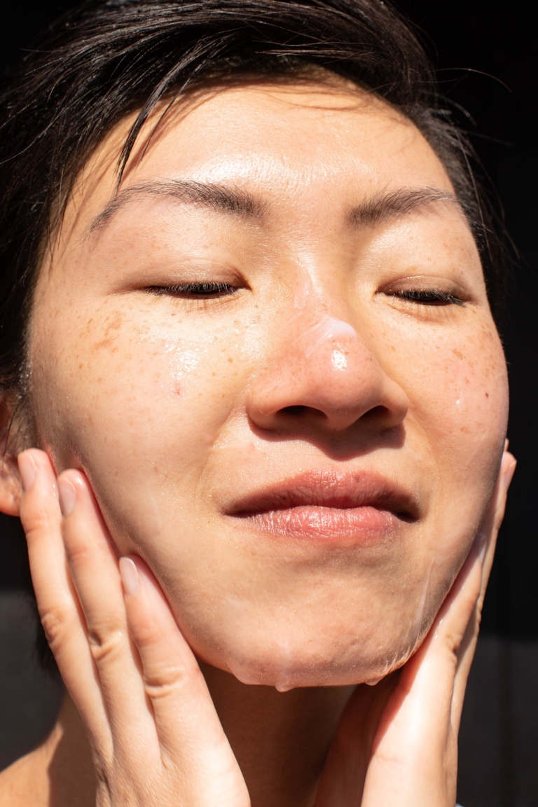 Closeup of person rubbing skincare cream on their face