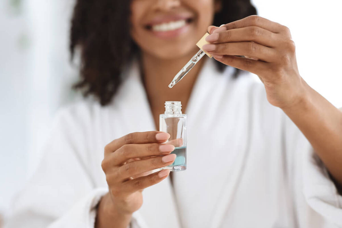 Woman Holding a Bottle and Dropper of Face Serum