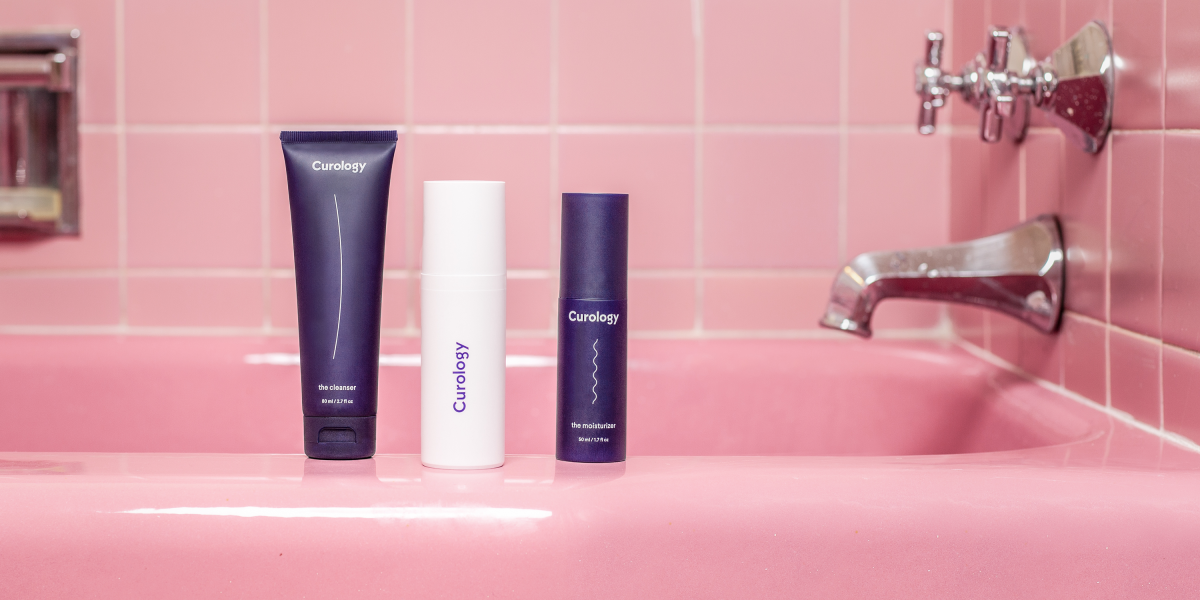 Curology bottles on bath tub with pink tiles