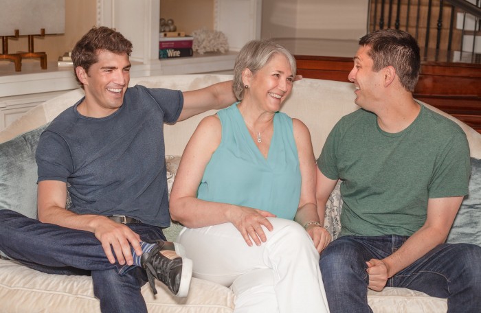 Family sitting on couch smiling (Nancy, David, and Glenn)