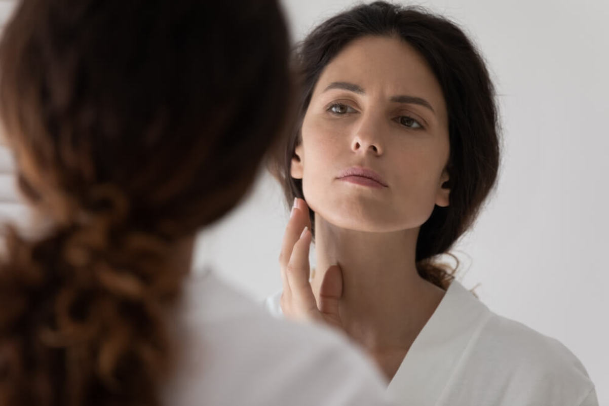 Woman looks at her dry facial skin on mirror