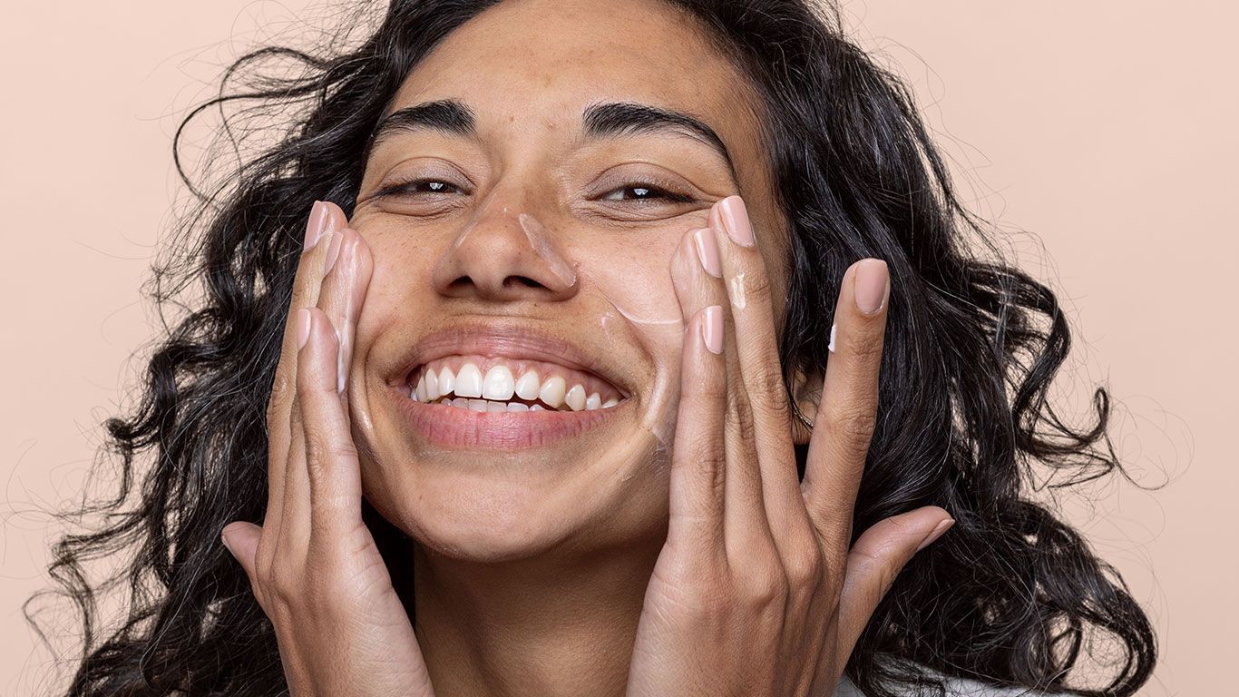 Woman rubbing skincare cream on her face