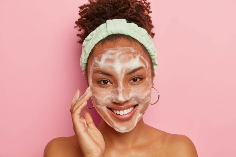 Woman with cleanser foam in face treating mouth acne with pink background