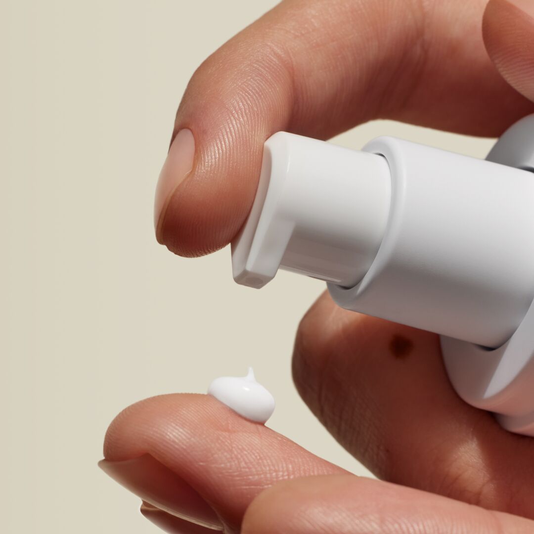 close up of hands pumping custom formula out of a white bottle