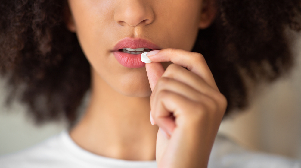 Woman putting pill in month