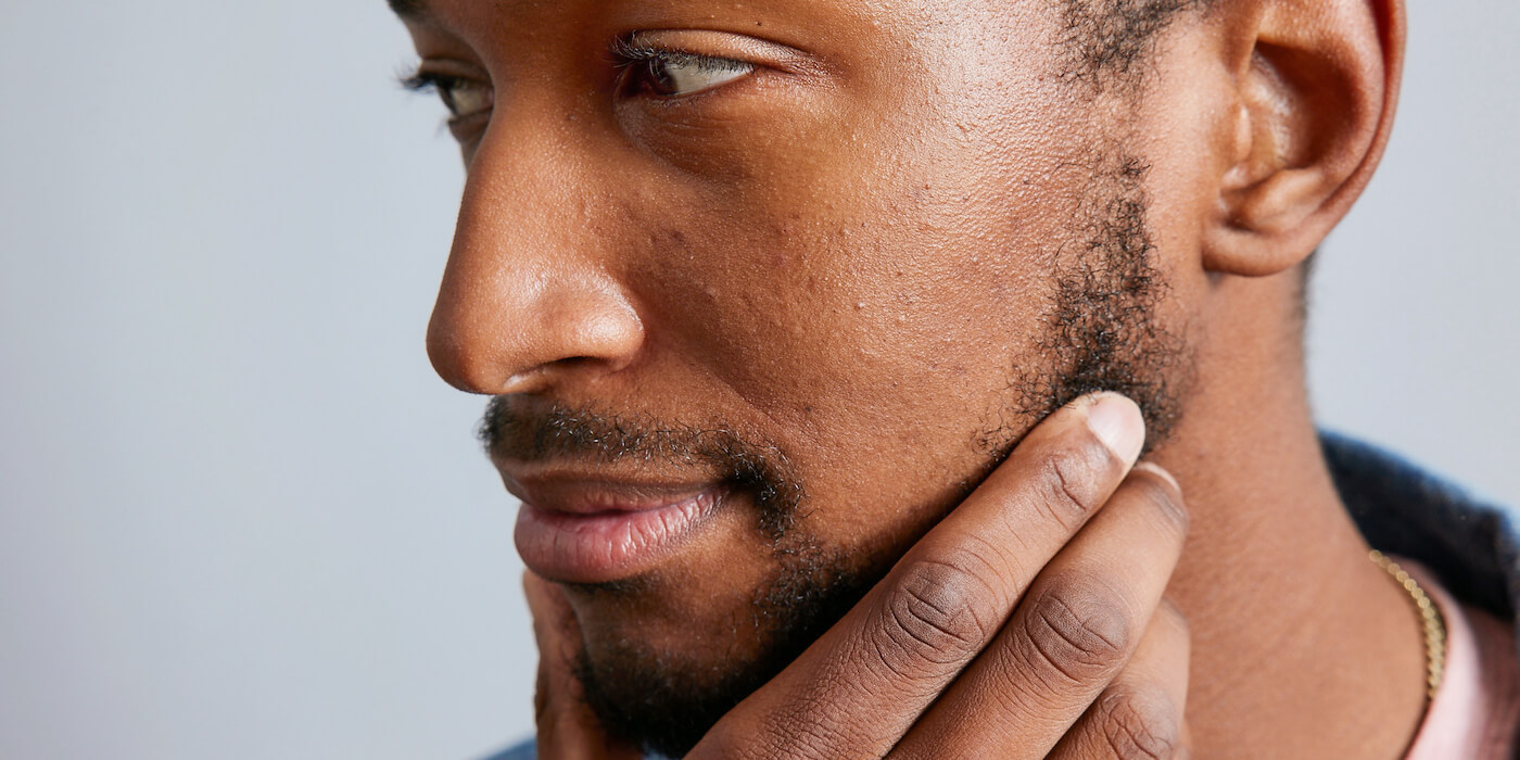 Millennial man with facial hair touching beard  
