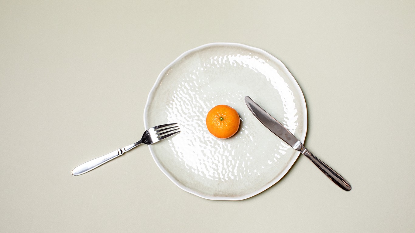 Orange on white plate with silverware