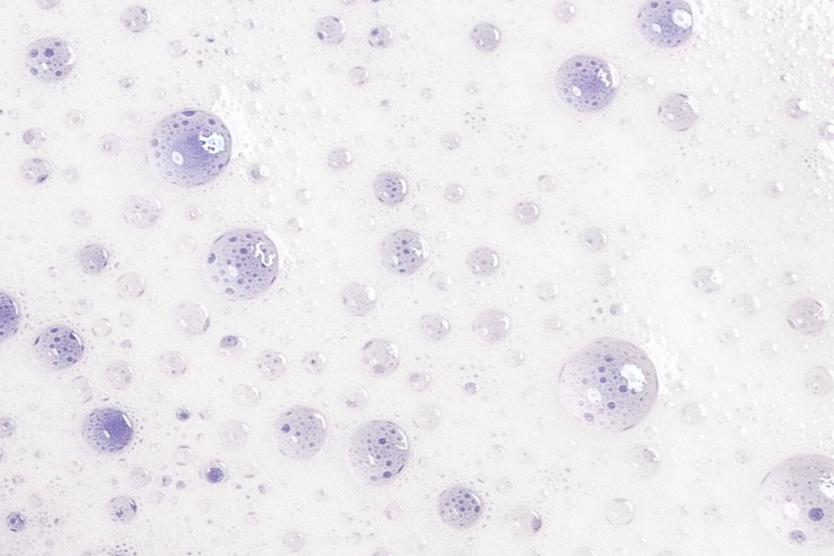 Closeup of beads of purple liquid against a white background