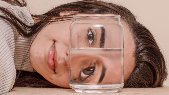 Woman with head on surface looking at glass of water