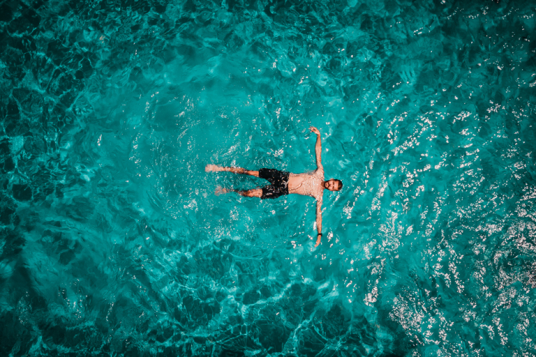 Drone areal view of young male in swimming pool floating