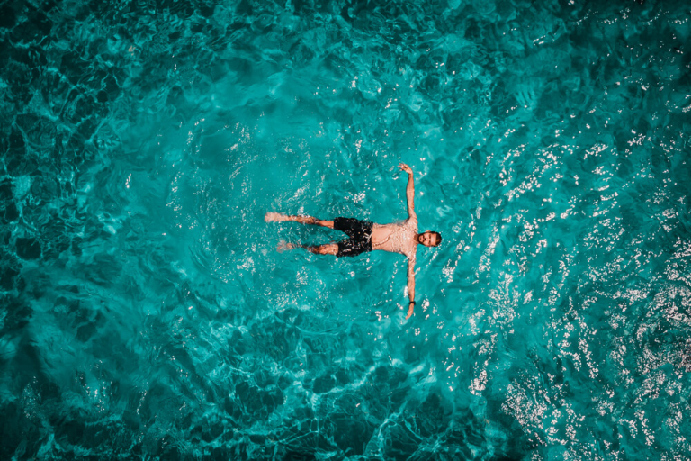 Drone areal view of young male in swimming pool floating