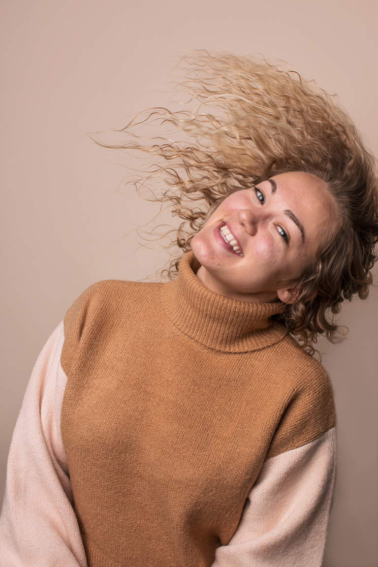 Woman with hair waving with brown sweater