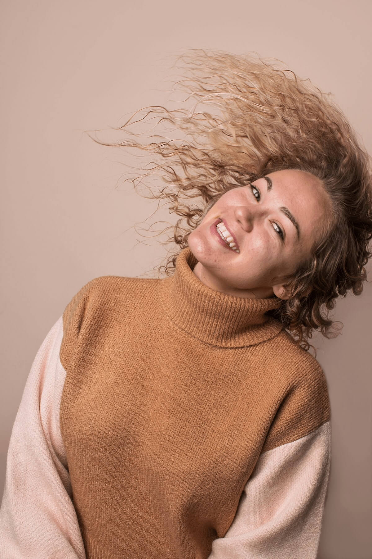 Woman with hair waving with brown sweater