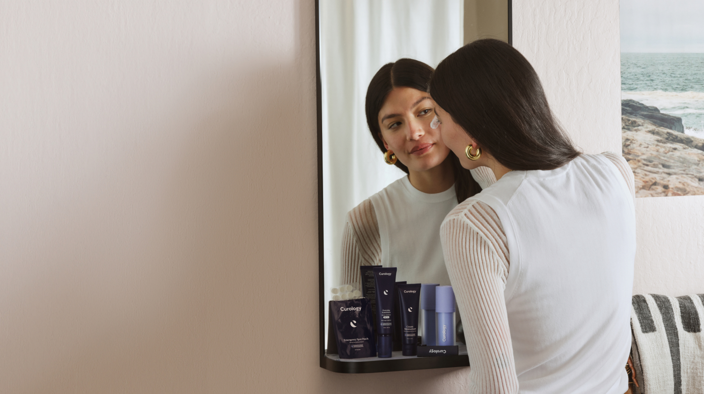 Brunette applying eye cream while looking in the mirror