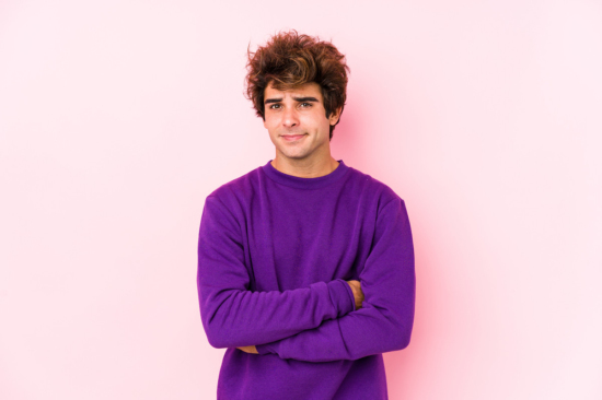 young man leaning on a pink wall